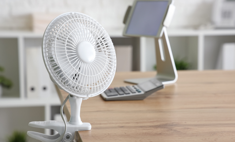 a white desk fan being used in an office